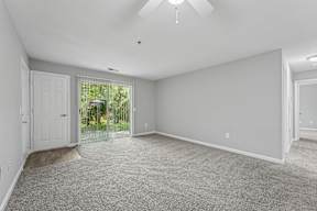 A spacious room with a carpeted floor and a ceiling fan.